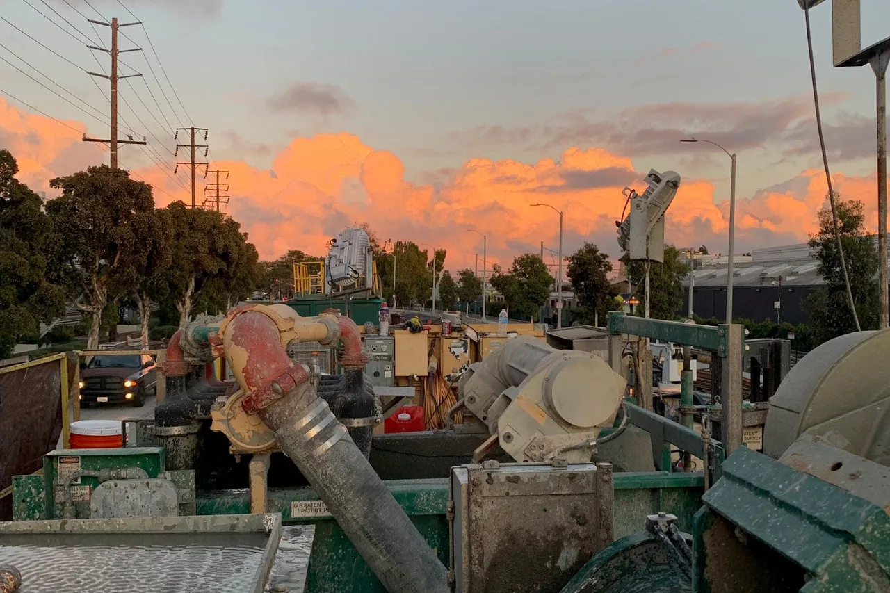 Drilling site at dusk with mud tank and shaker unit
