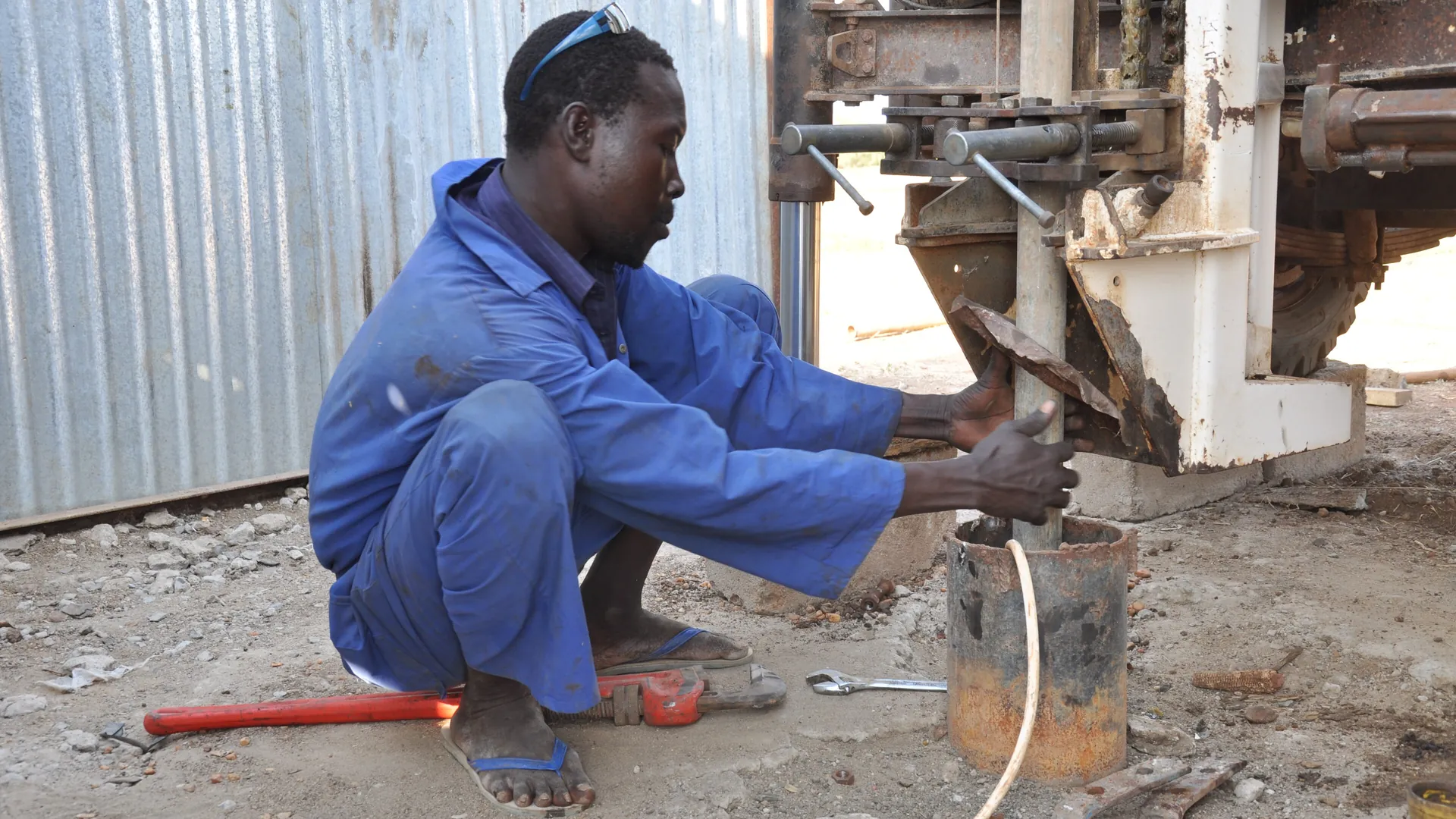 Hydrogeologist operating the control panel of a borehole drilling rig